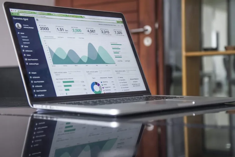 A laptop on a glass desk showing a website traffic analytics dashboard