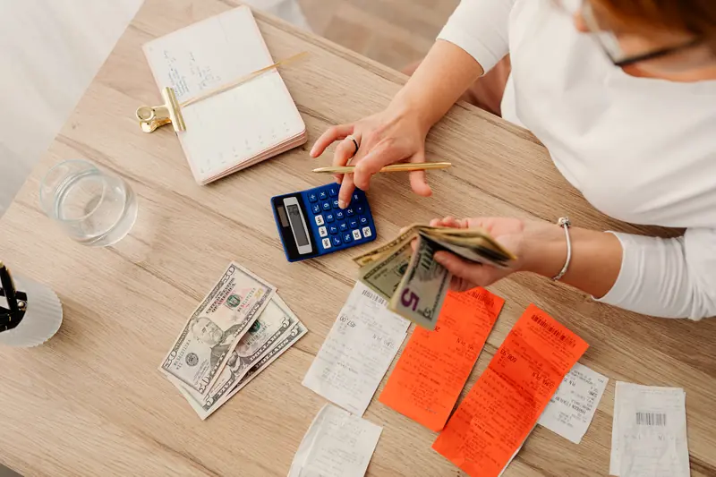 A desk with cash, receipts, and a calculator while resetting a household budget
