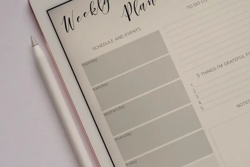 A tablet showing a weekly planner template with a stylus beside it