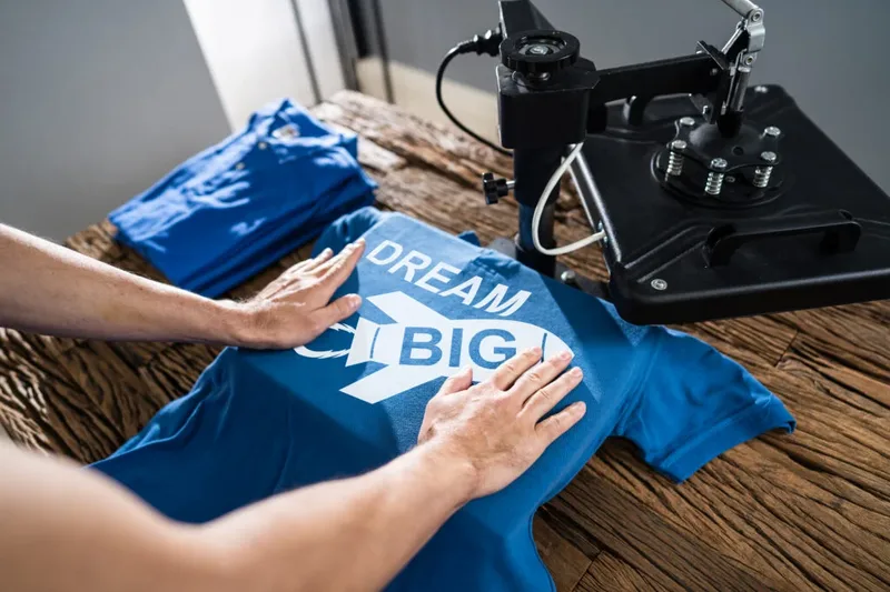 Hands smoothing a freshly printed t-shirt under a heat press