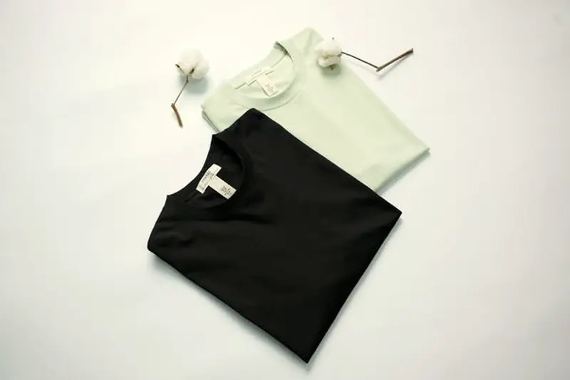 Folded blank t-shirts in black and mint on a clean surface, ready for printing