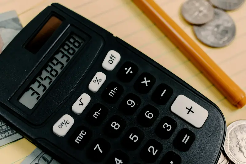 A calculator and coins on a desk while adding up startup costs