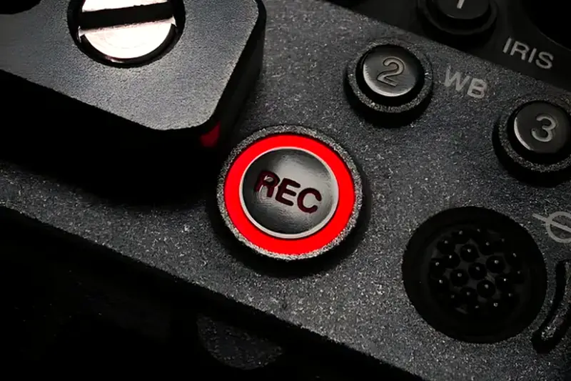 A close-up of a video camera's red record button